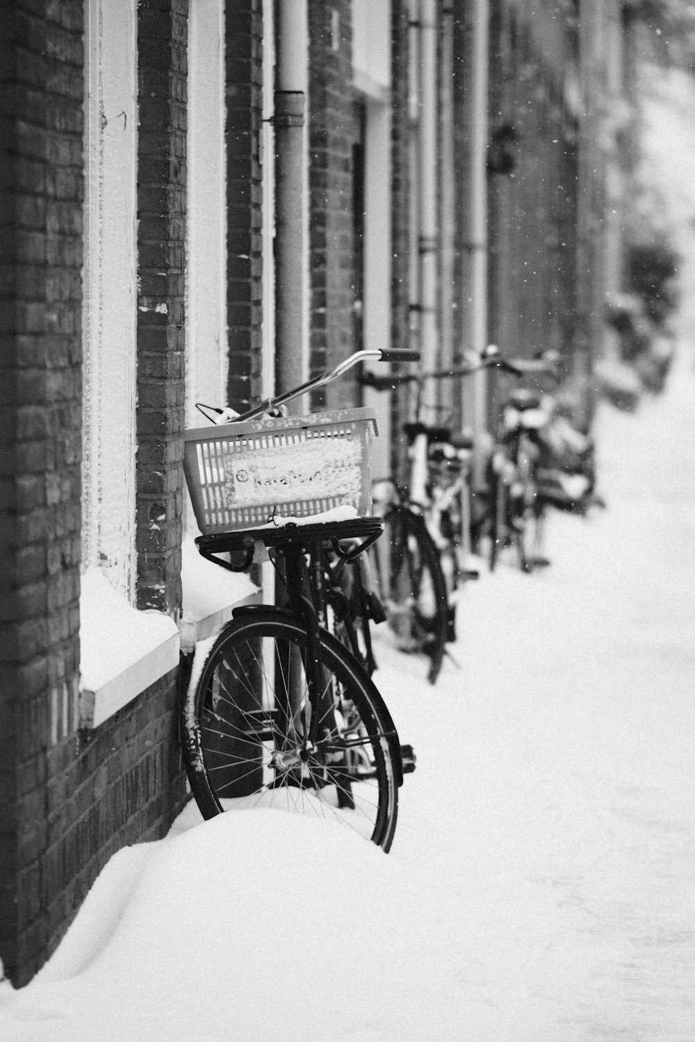 Bicicleta estacionada junto a una pared de ladrillo en fotografía en escala de grises