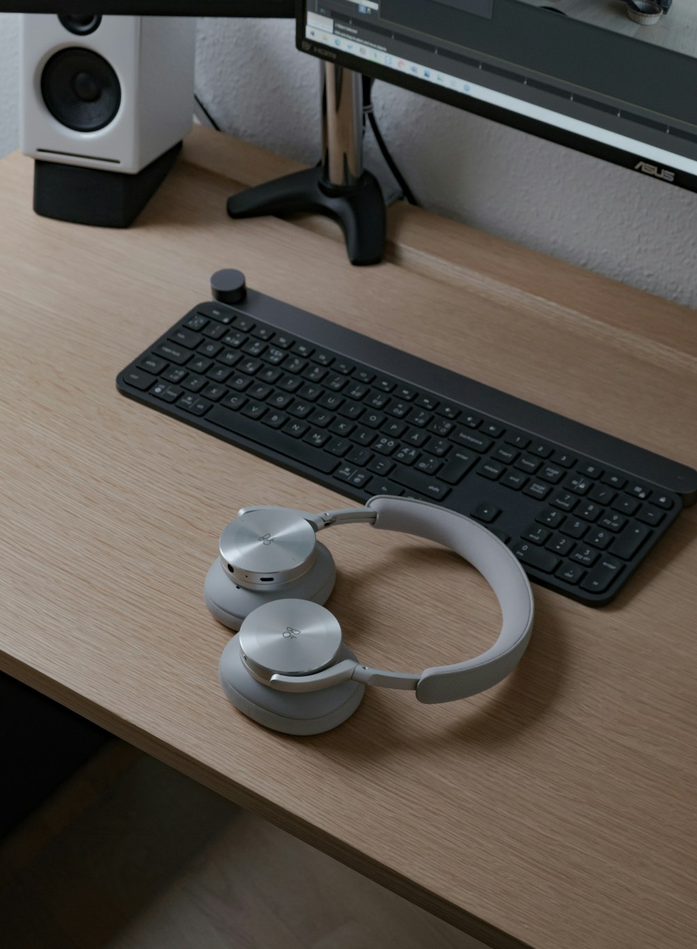 teclado de computadora negro junto a auriculares blancos