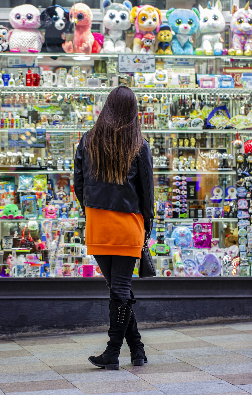 woman in black long sleeve shirt and orange skirt standing in front of store