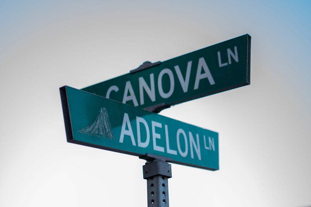 two green street signs sitting on top of a metal pole