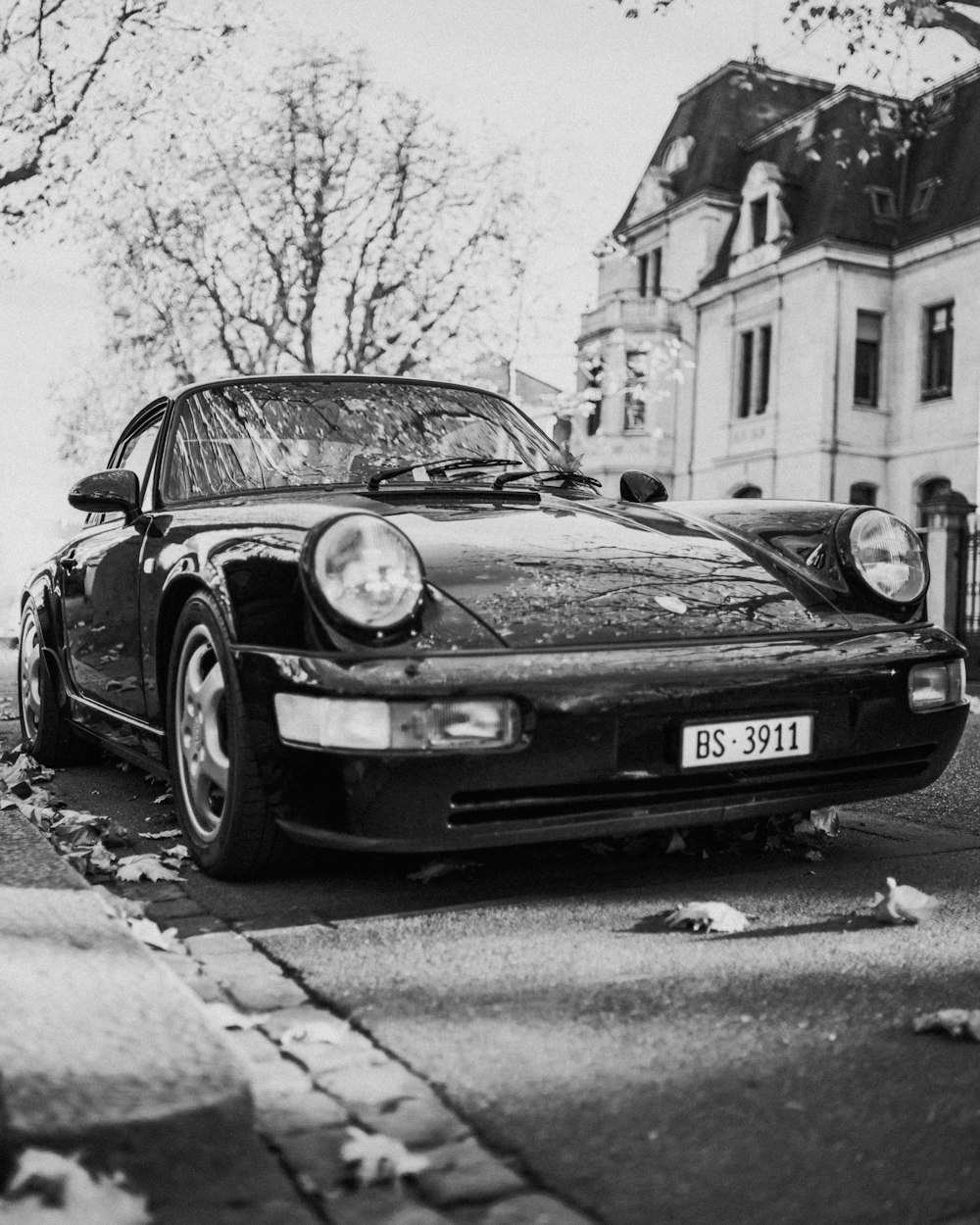 grayscale photo of classic car parked on sidewalk