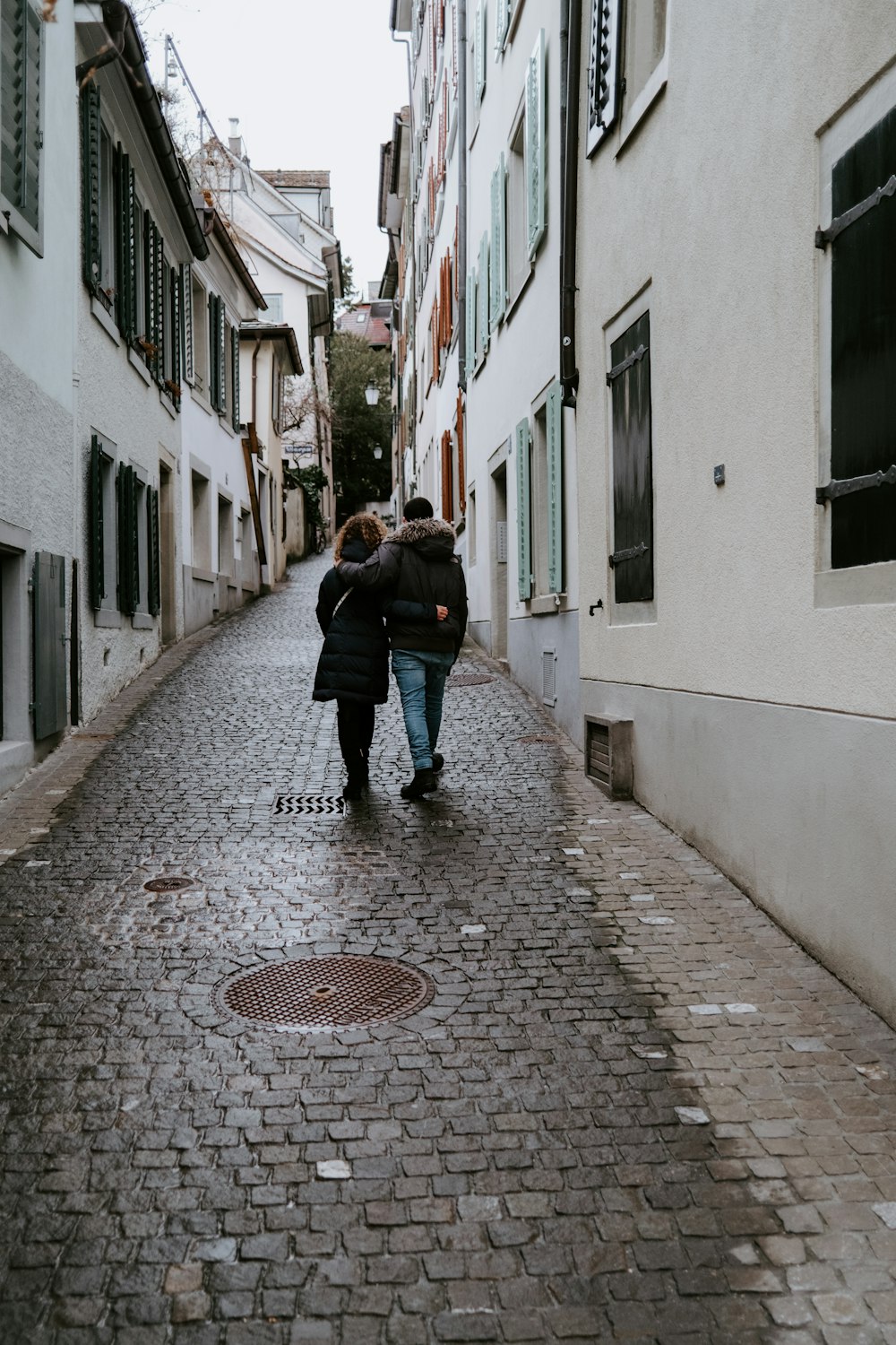 woman in black jacket walking on sidewalk during daytime