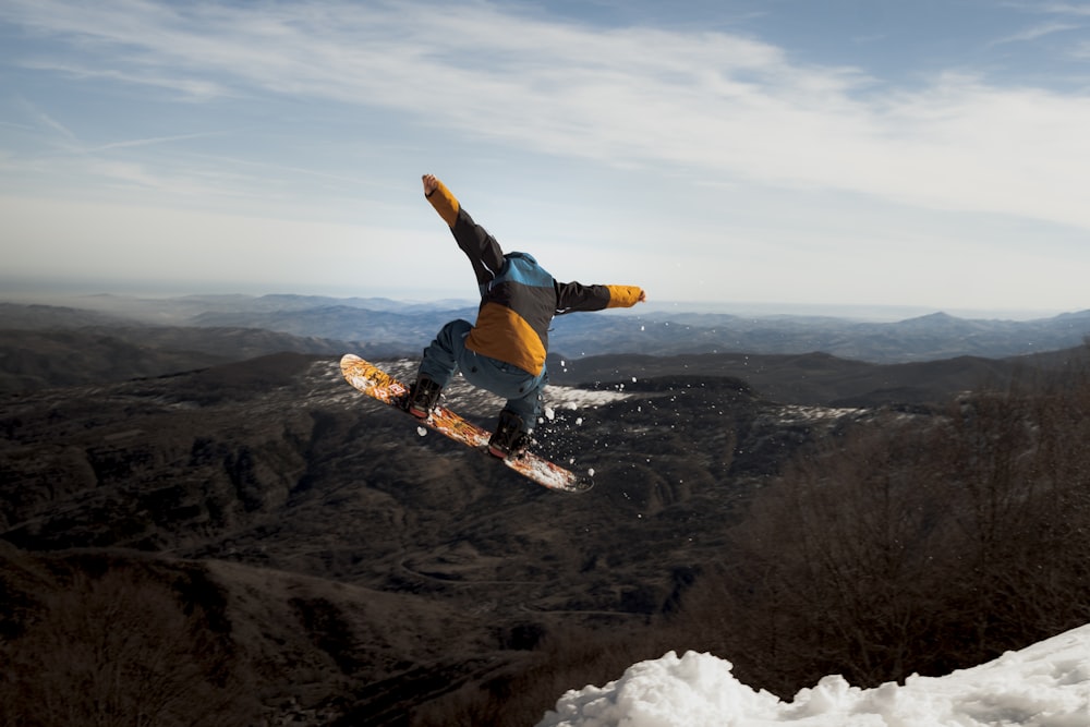 Hombre con chaqueta azul y pantalones negros haciendo esquí en la nieve durante el día