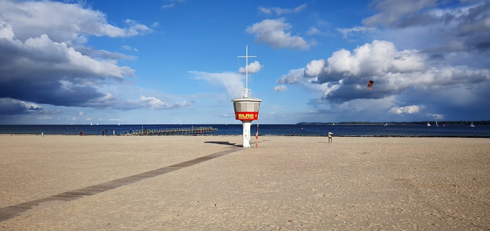 white and red lifeguard tower on beach shore under blue sky during daytime