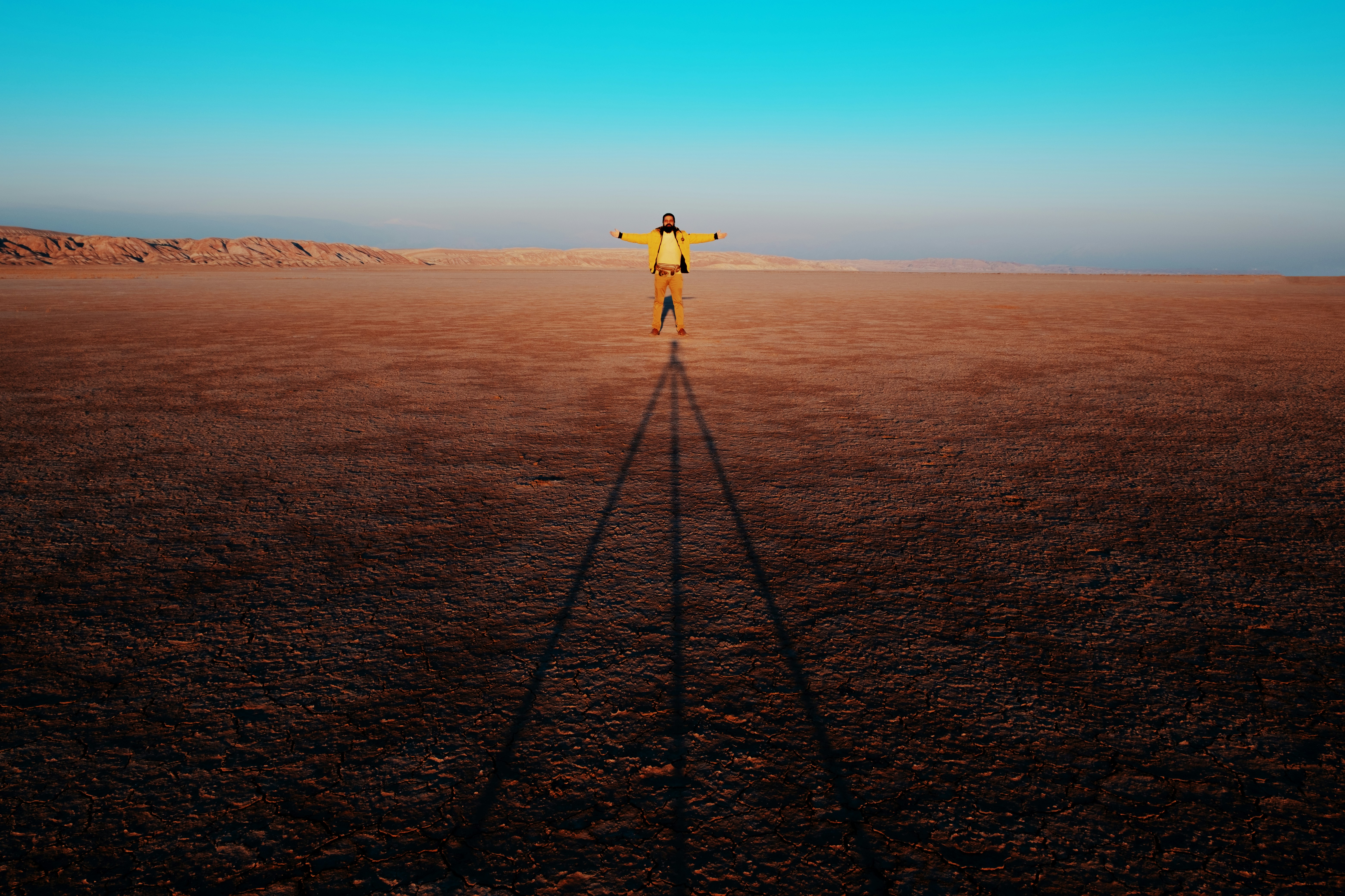 person in yellow shirt and black pants standing on black metal tripod during daytime