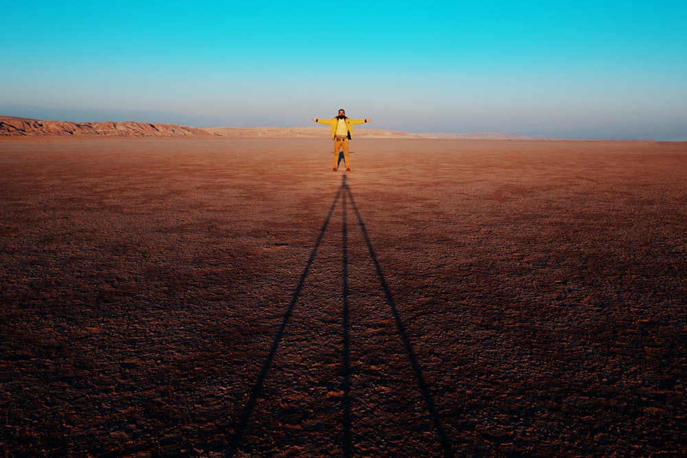 person in yellow shirt and black pants standing on black metal tripod during daytime