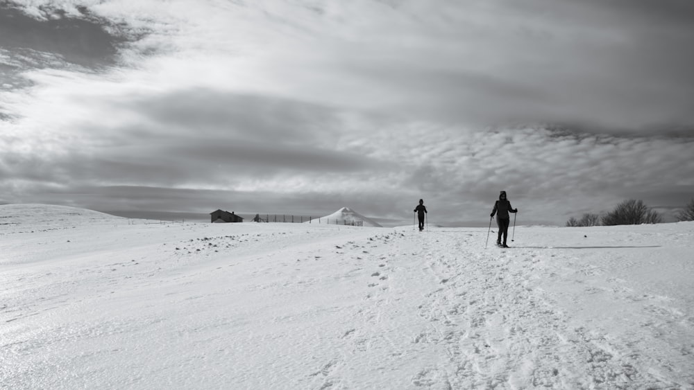 2 pessoas caminhando em solo coberto de neve durante o dia