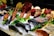 A display of fresh seafood including lobsters, fish, and shellfish is arranged on a bed of ice. Wrapped products, likely packaged seafood, are also present. The setup is enhanced with greens like lettuce for decoration, and various seafood items are placed around for an appealing presentation.