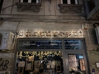 An inviting storefront with the Pageturner Hub sign glowing warmly in the early evening.