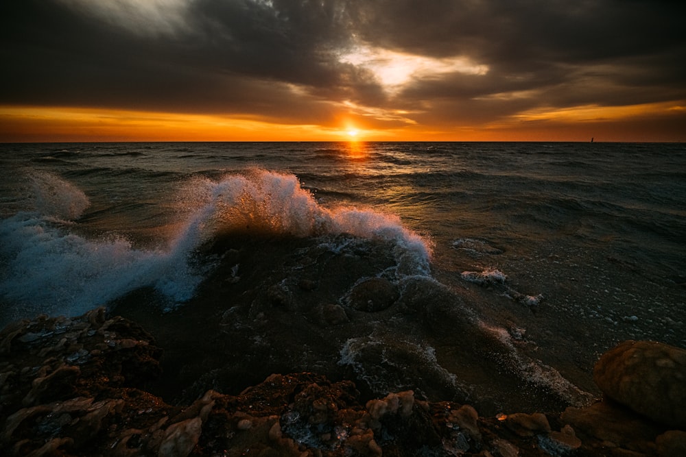 the sun is setting over the ocean with waves