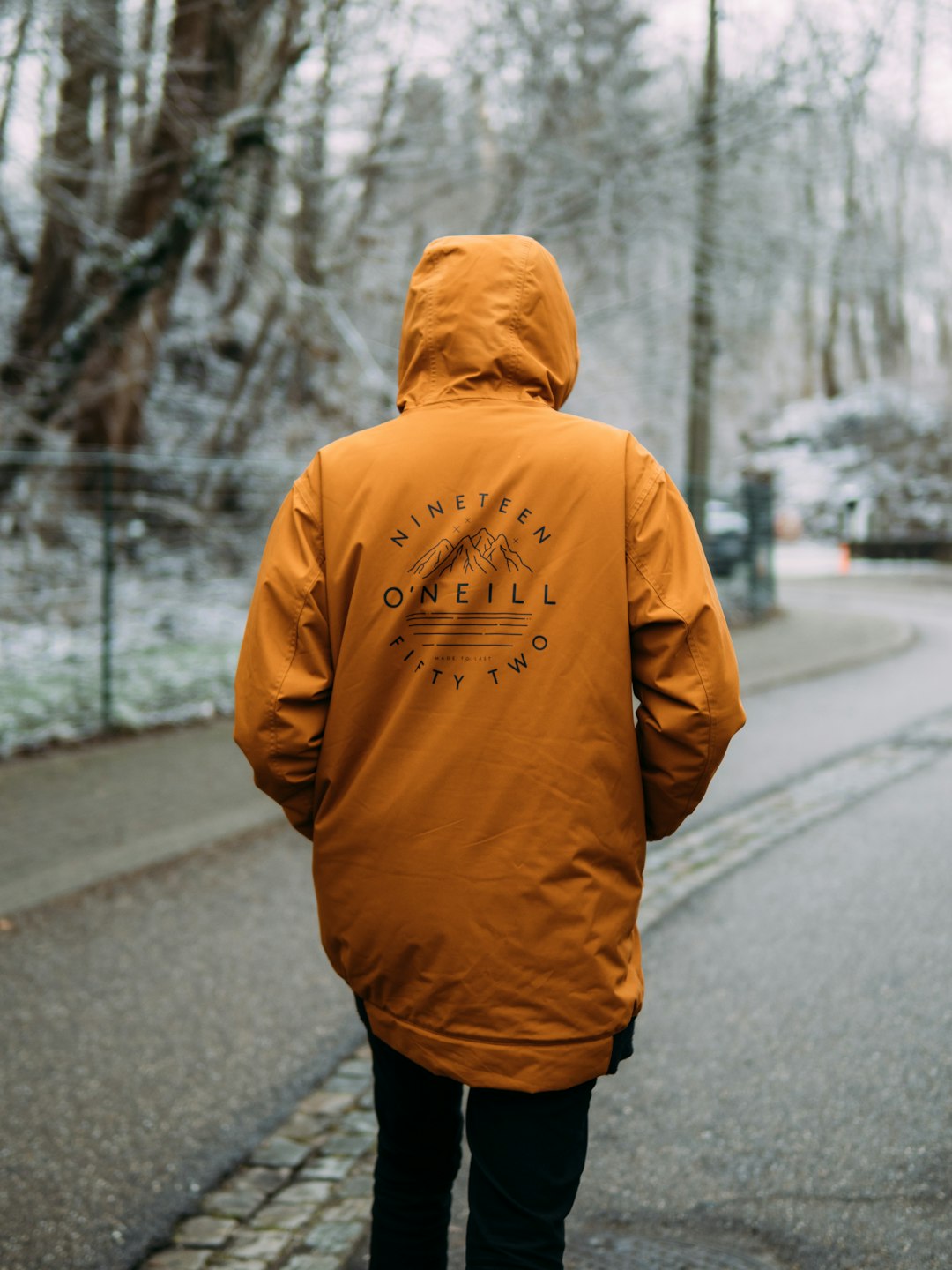 man in yellow hoodie standing on road during daytime