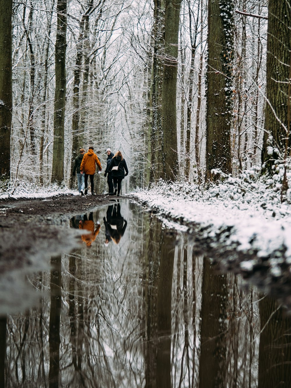 person in black jacket and orange backpack walking on snow covered ground during daytime