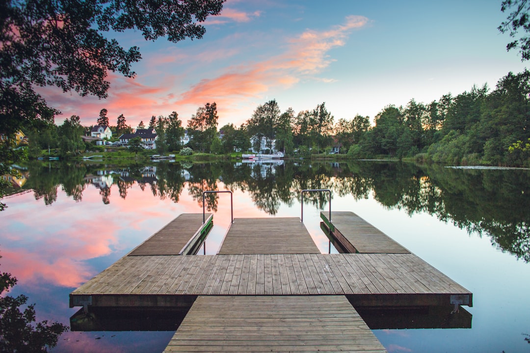 brown wooden dock on lake during sunset