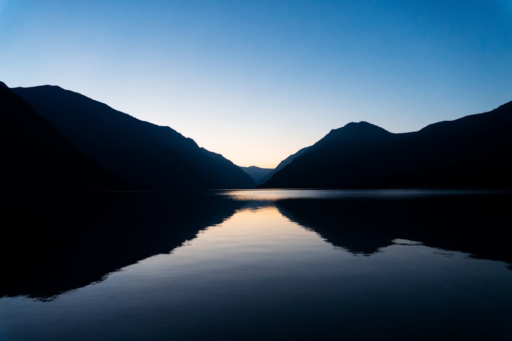 body of water near mountain during daytime