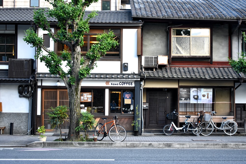 昼間、茶色と白のコンクリートの建物の脇に停車している黒い自転車