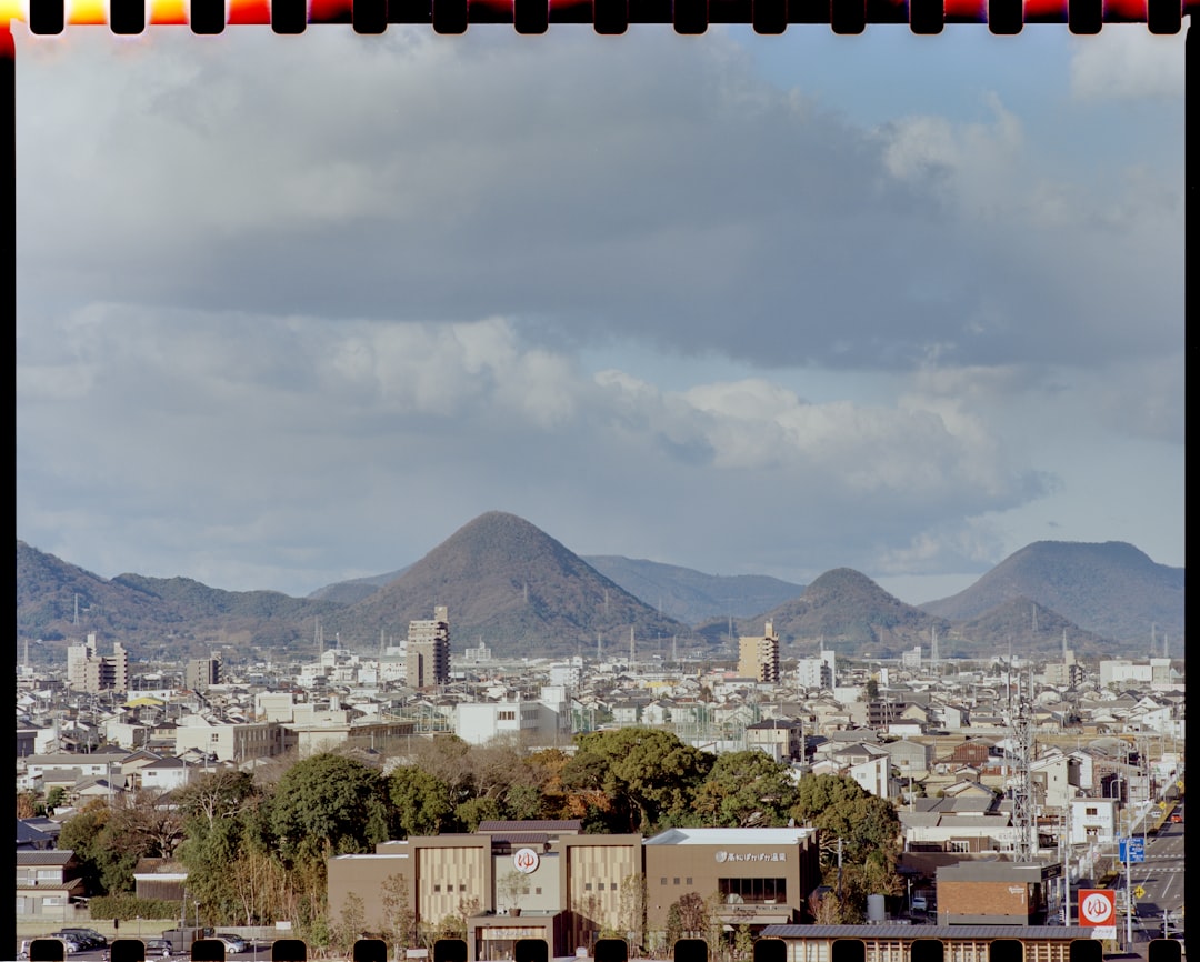 city buildings near mountain under white clouds during daytime