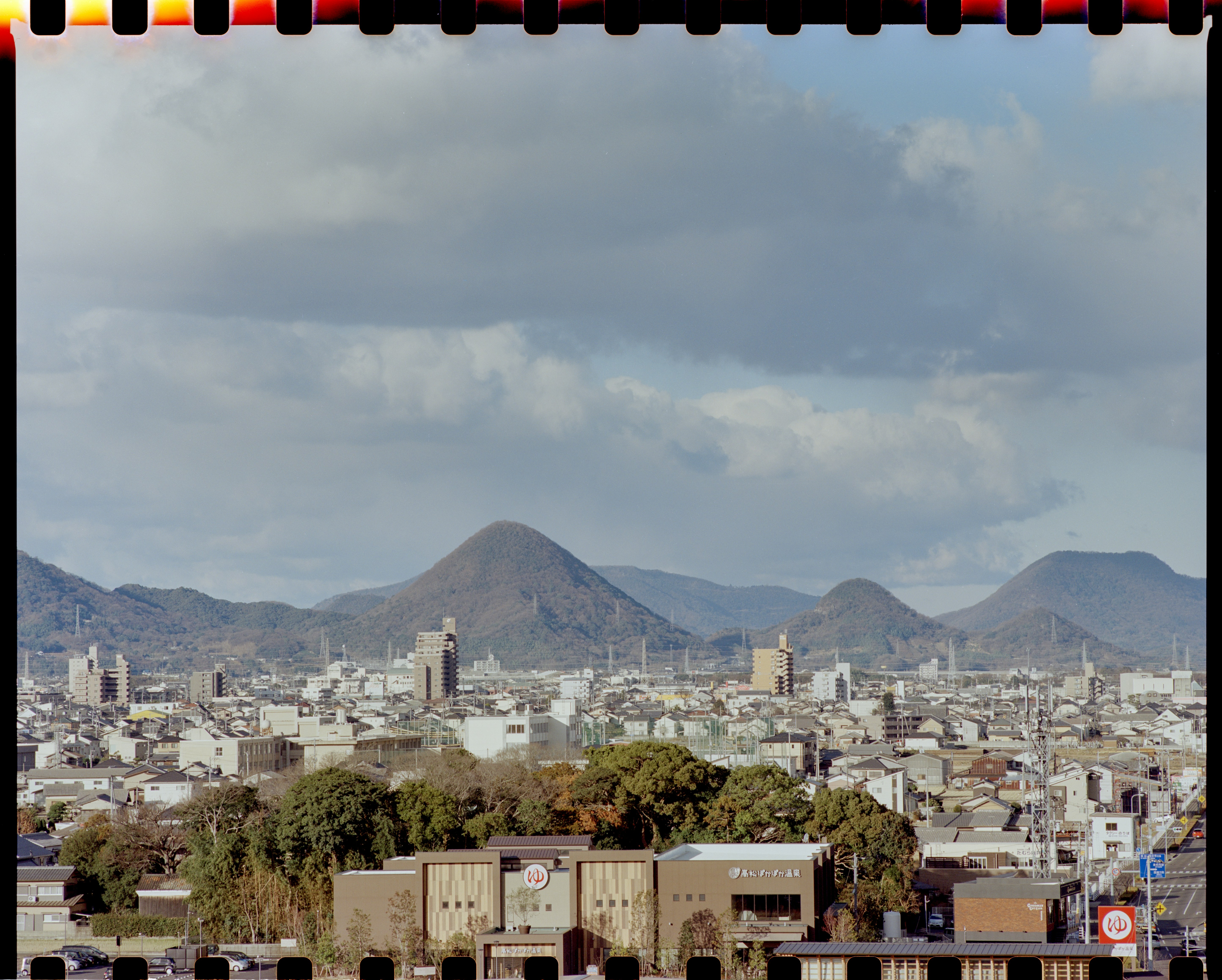 city buildings near mountain under white clouds during daytime