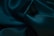A close-up view of lustrous, dark green silk fabric with smooth textures and gentle folds creating an elegant and luxurious appearance.