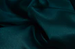 Vibrant emerald green silk fabric draped softly to highlight smooth texture