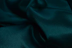 Vibrant emerald green silk fabric draped softly to highlight smooth texture