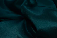 Vibrant emerald green velvet fabric catching soft light, showing its plush surface.