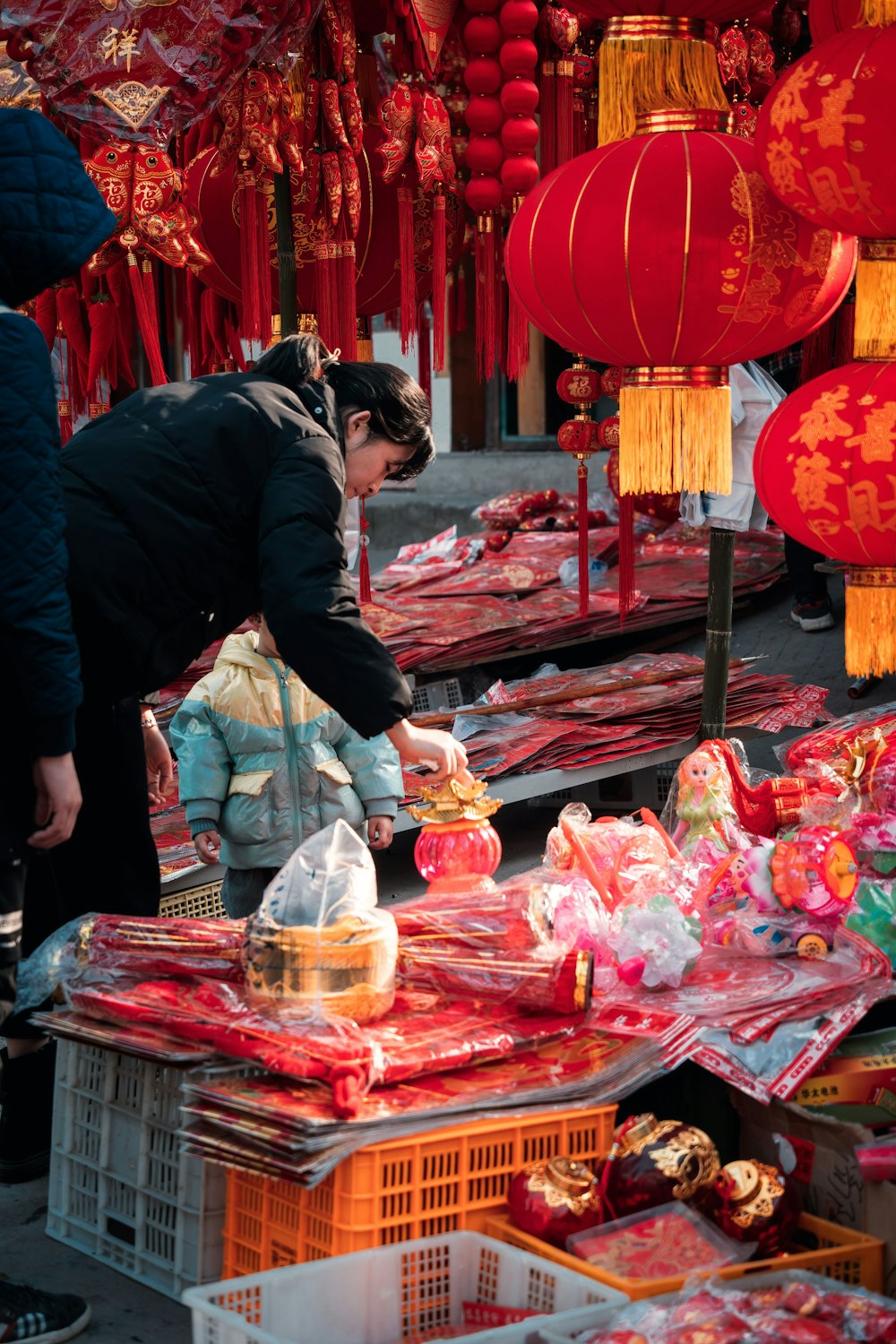 man in black jacket and white pants standing in front of food stall