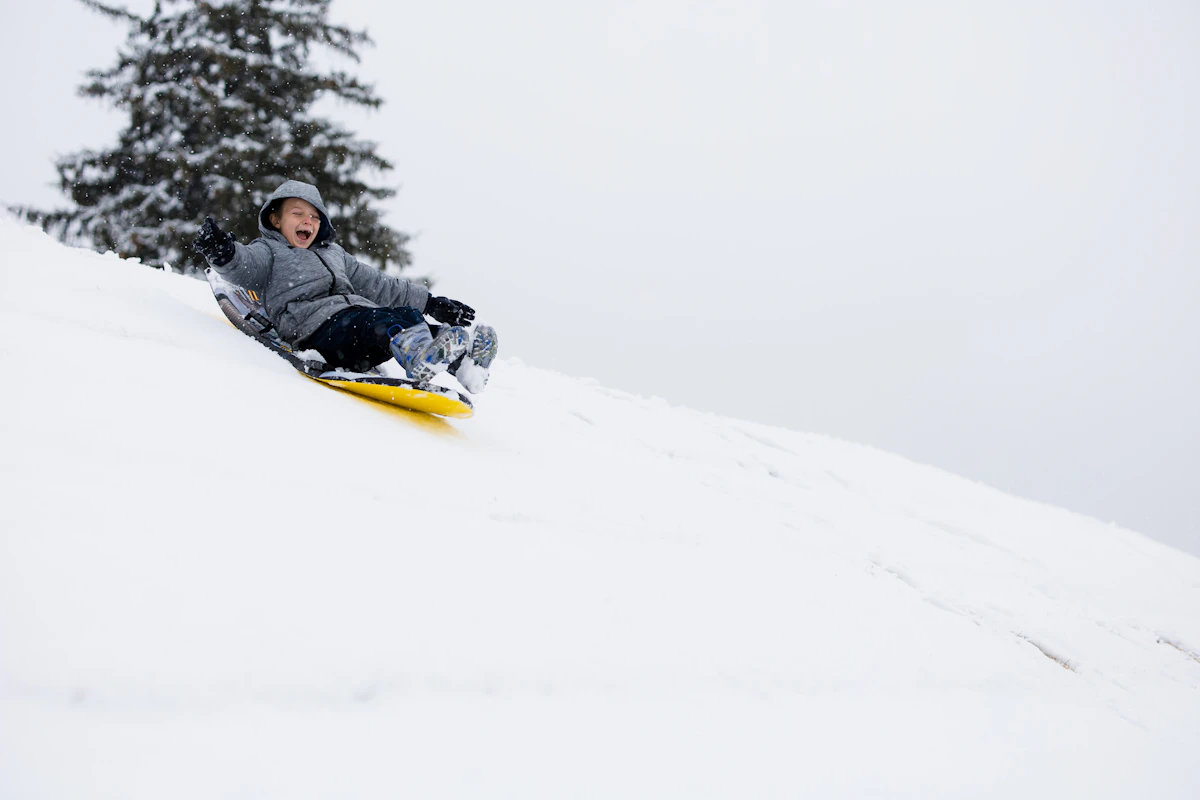 Person riding a sled down a snow-covered slope