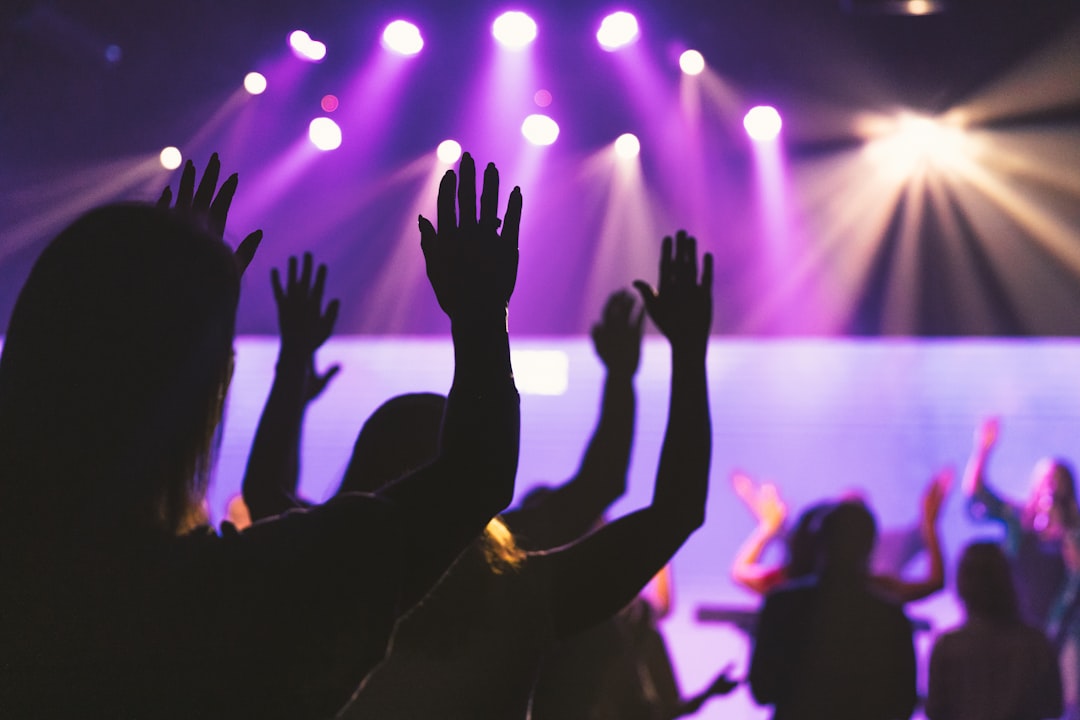 people raising their hands in front of a concert