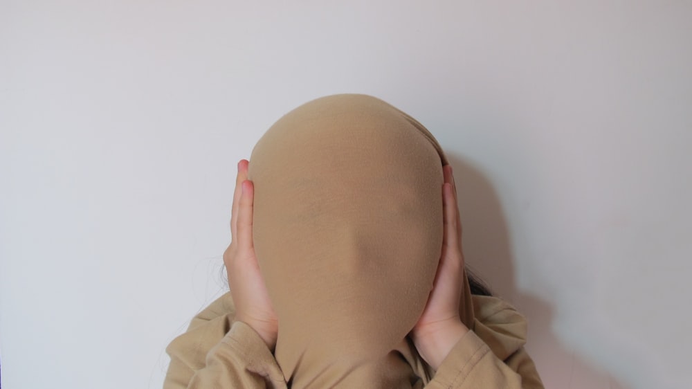 person in beige jacket holding brown egg