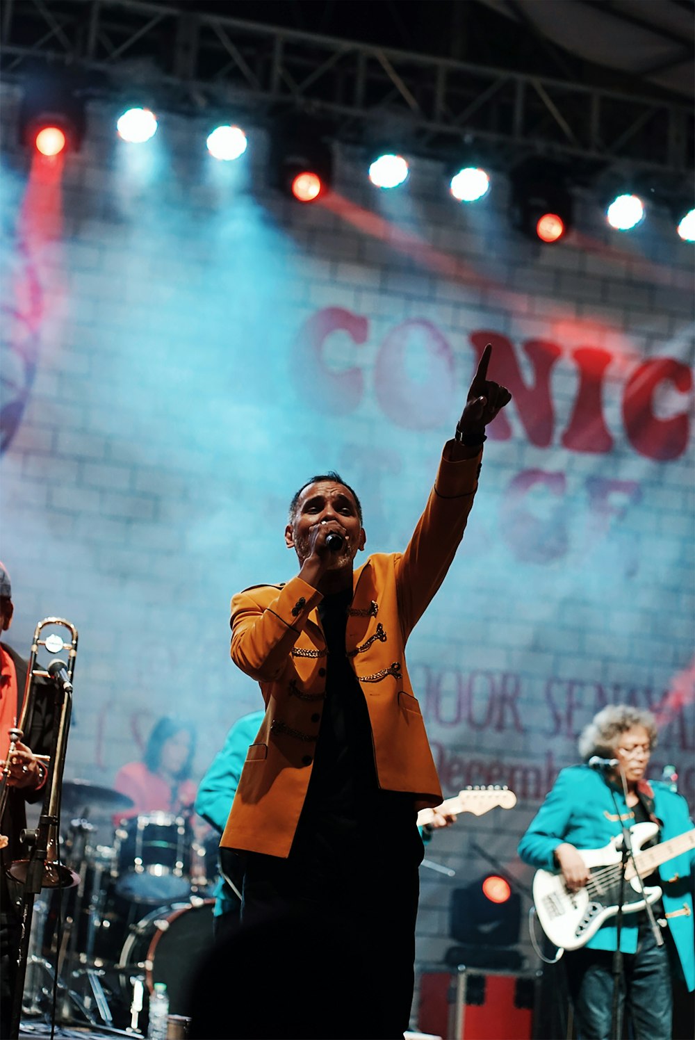 man in brown coat singing on stage