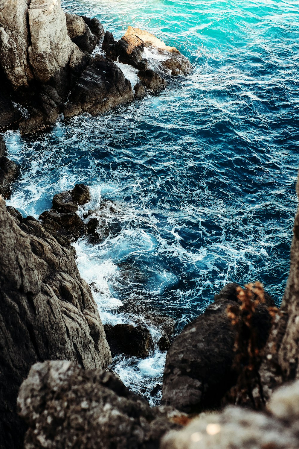 昼間の青い海のそばの茶色の岩山