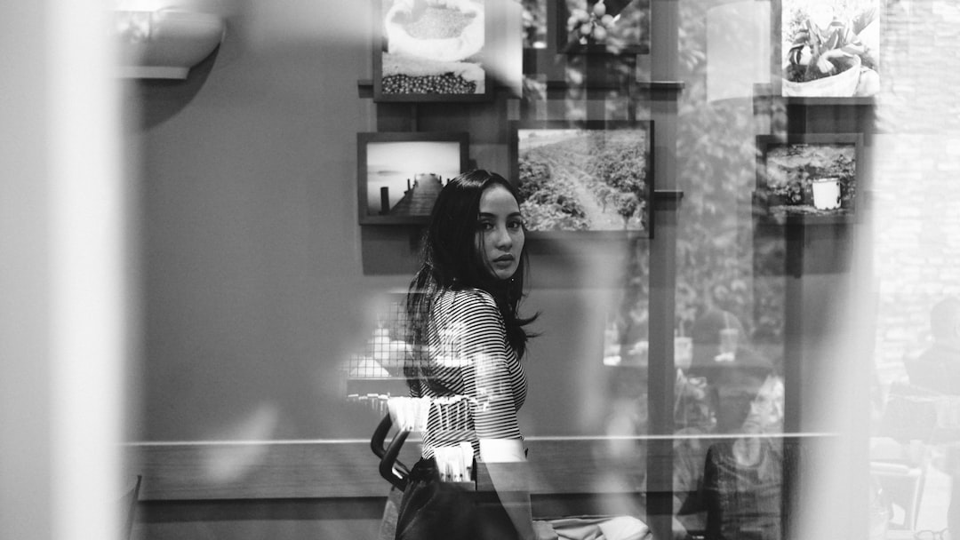 woman in black and white stripe long sleeve shirt standing beside glass wall