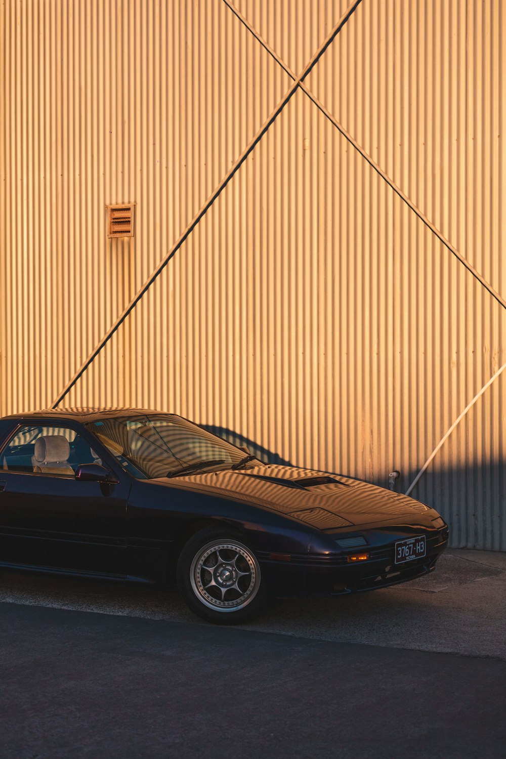 black porsche 911 parked beside brown wall