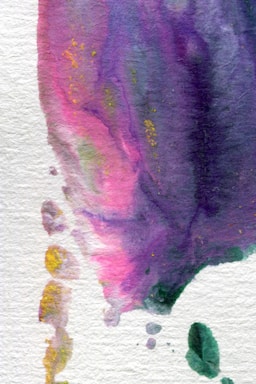 A watercolor painting with an abstract design featuring flowing gradients of purple, pink, and hints of yellow. The texture is visible, and the colors blend into each other creating a calming effect. There are small splashes of green and yellow towards the edges.