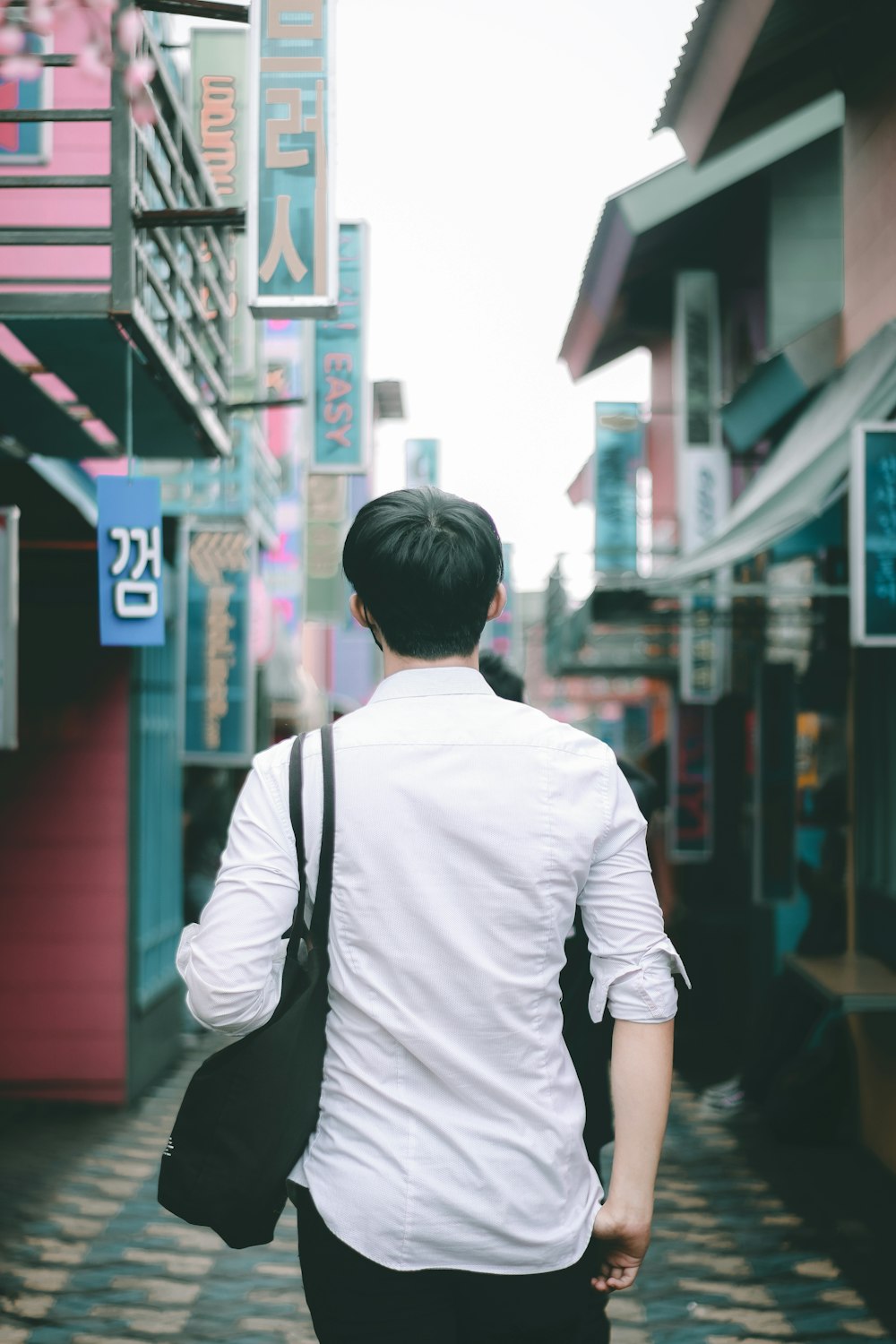 man in white shirt and black jacket walking on sidewalk during daytime