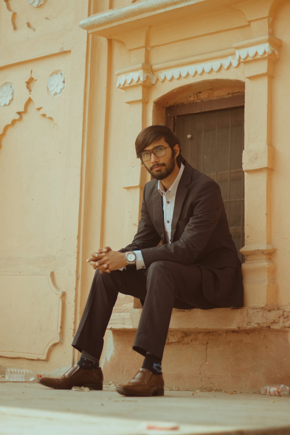 a man sitting on a ledge in front of a building