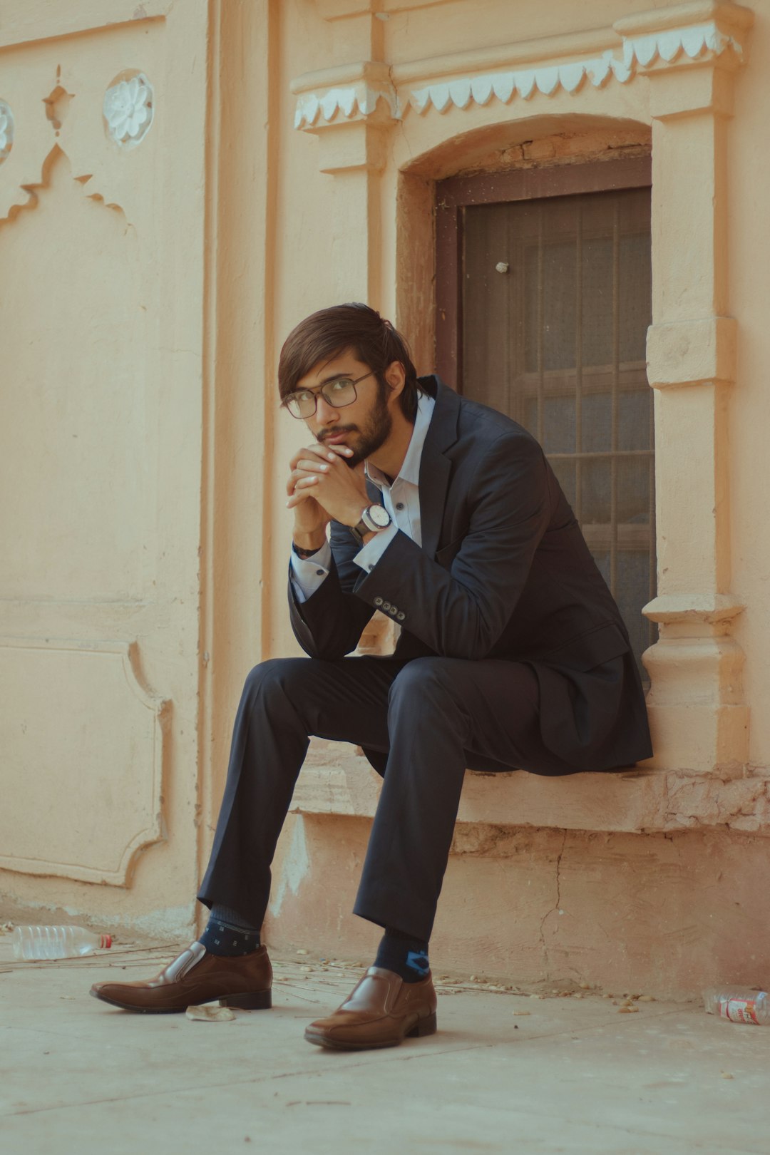 man in black suit jacket and black pants sitting on concrete bench