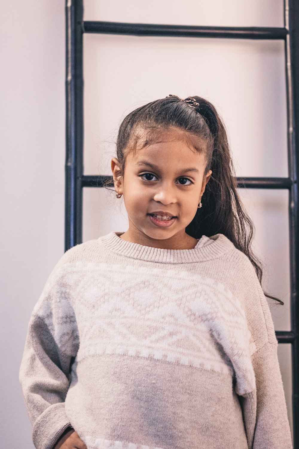 girl in white sweater standing near white wall