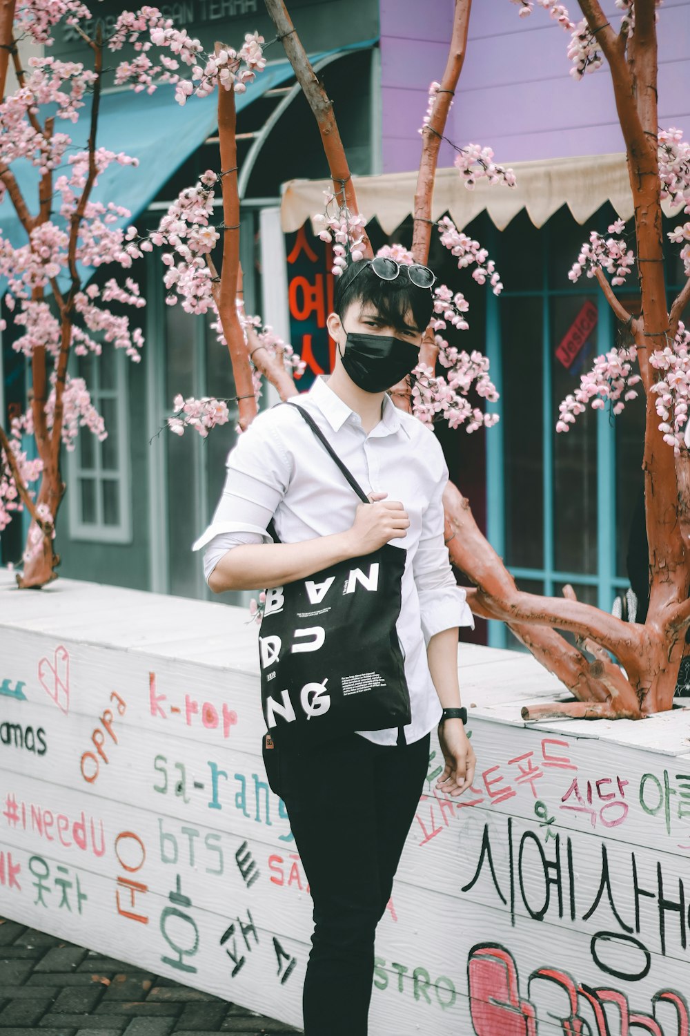 man in white crew neck t-shirt and black pants standing near white and red kanji