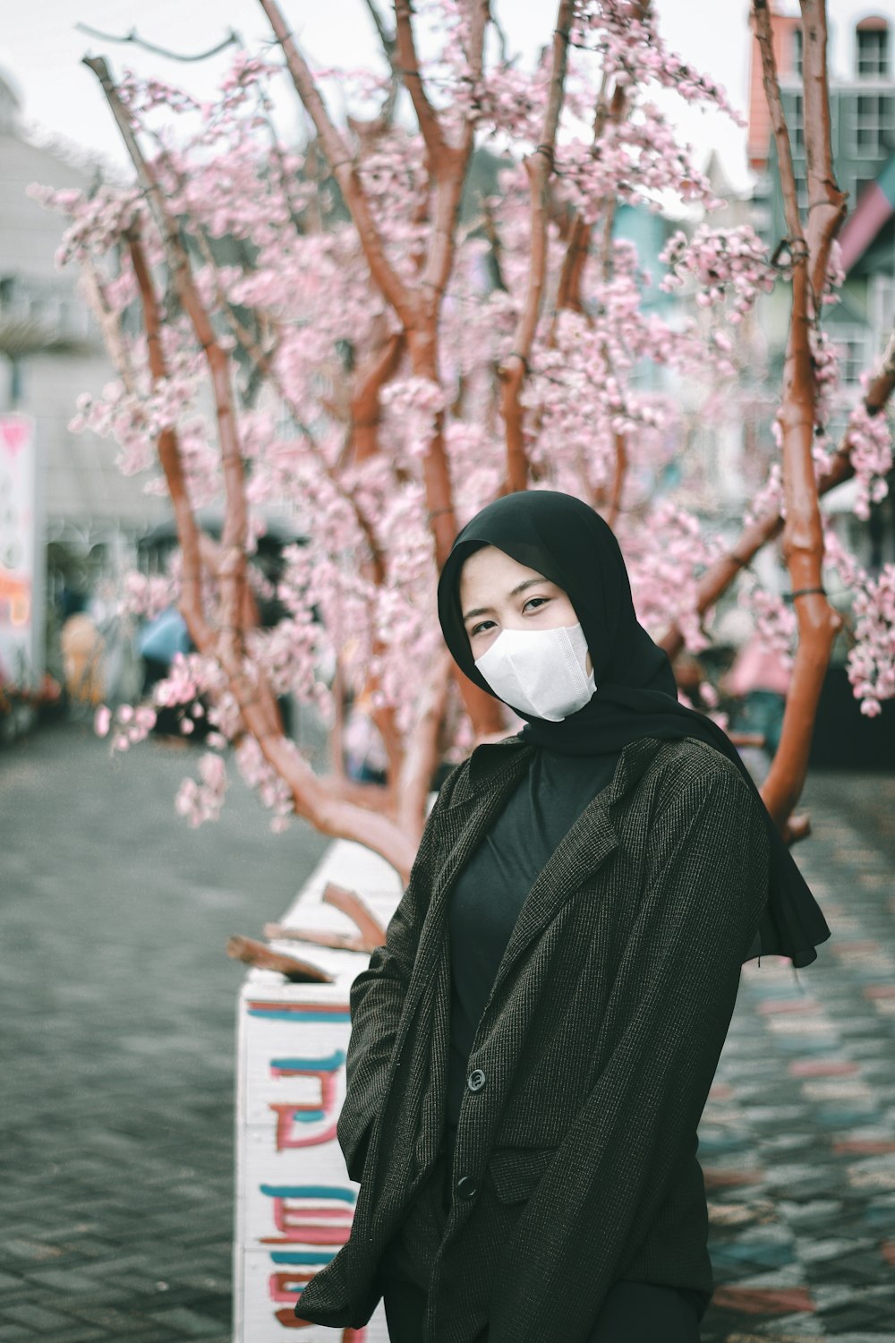 woman in black hijab standing near brown wooden bench during daytime