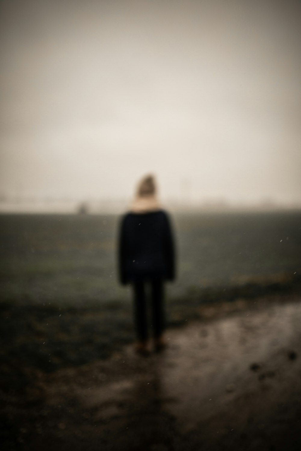 woman in black long sleeve dress standing on gray sand during daytime