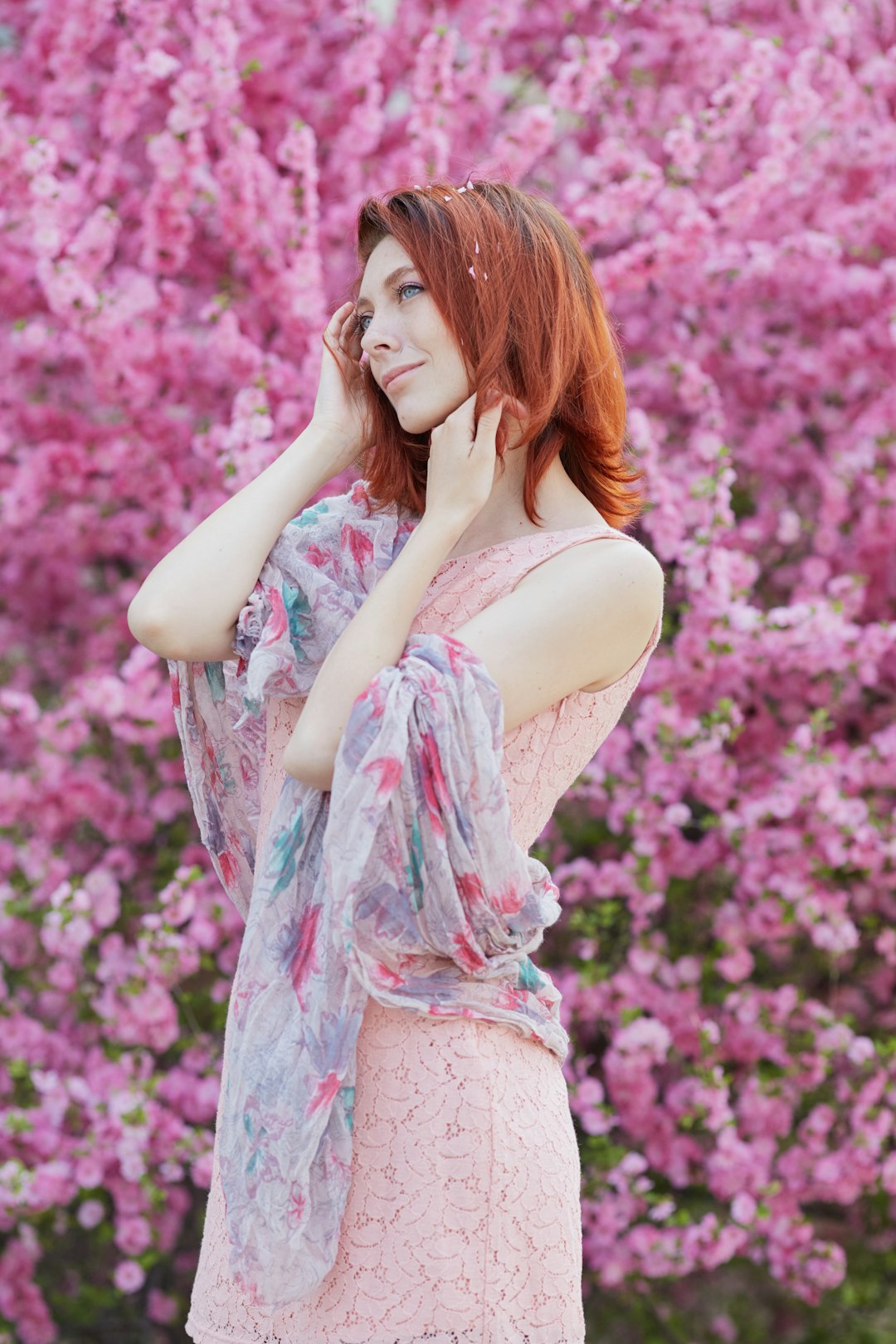 woman in white tank top and pink floral skirt standing near pink flowers