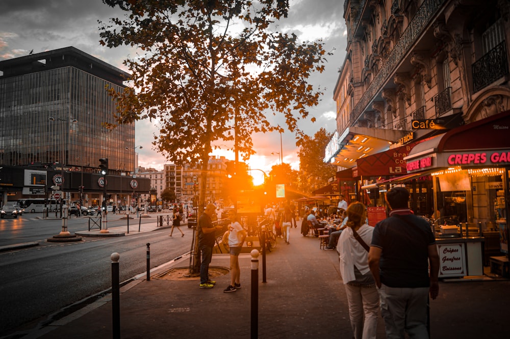 people walking on sidewalk during sunset