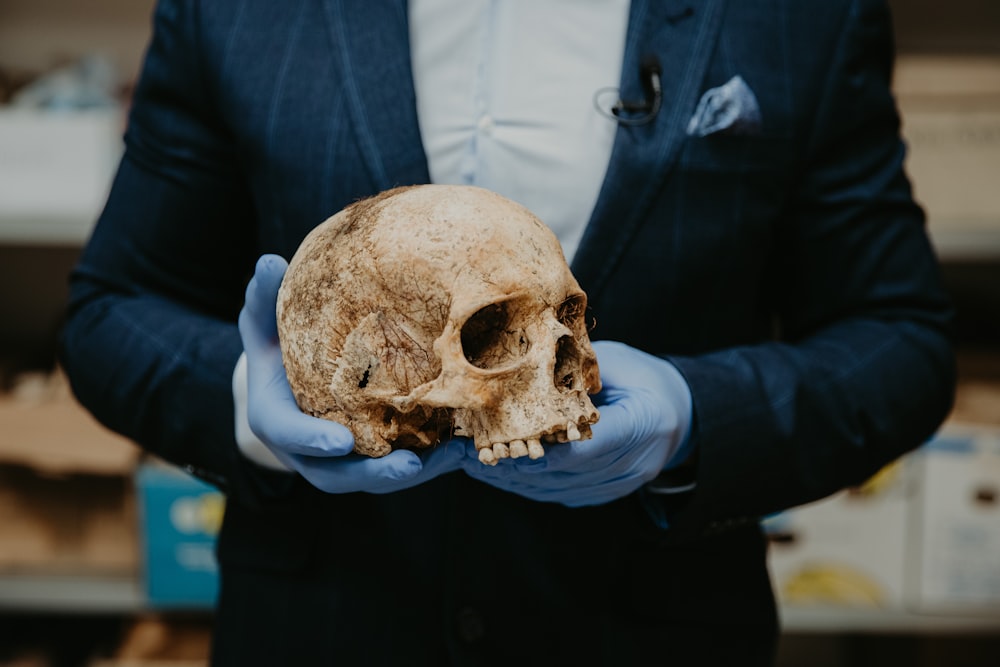 person in blue long sleeve shirt holding brown skull