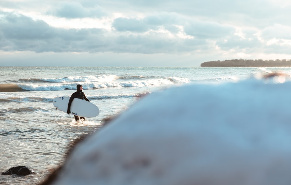 person in black shirt and black pants walking on seashore during daytime