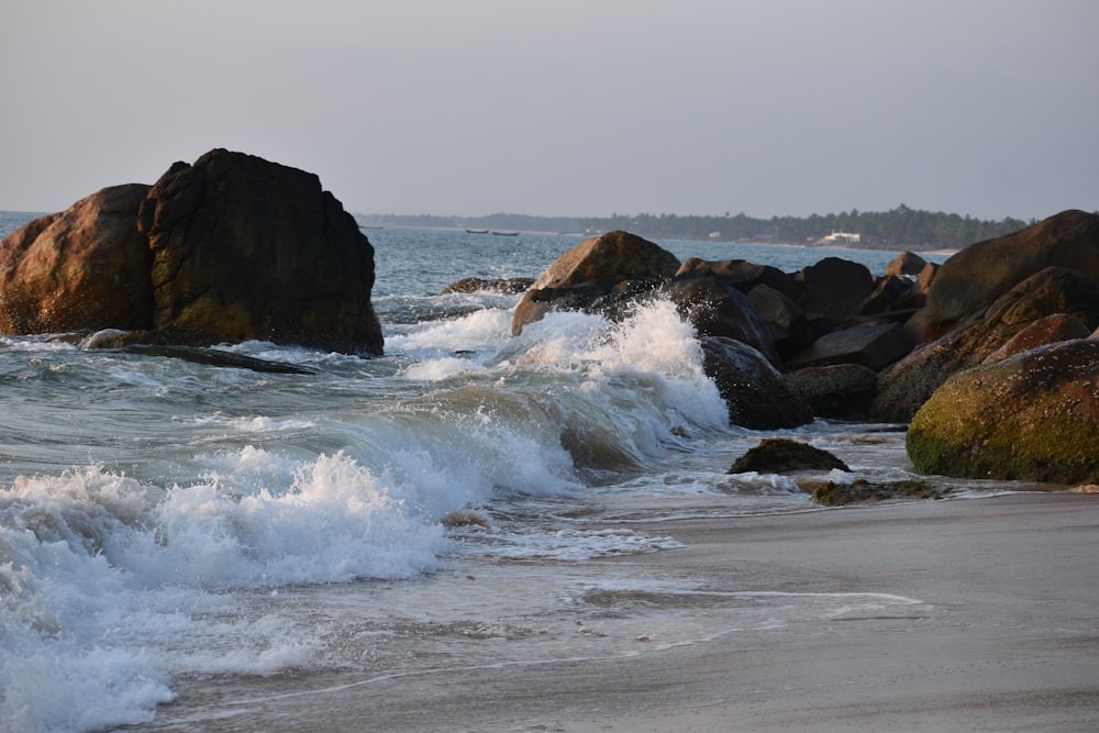 ocean waves crashing on black rock formation during daytime