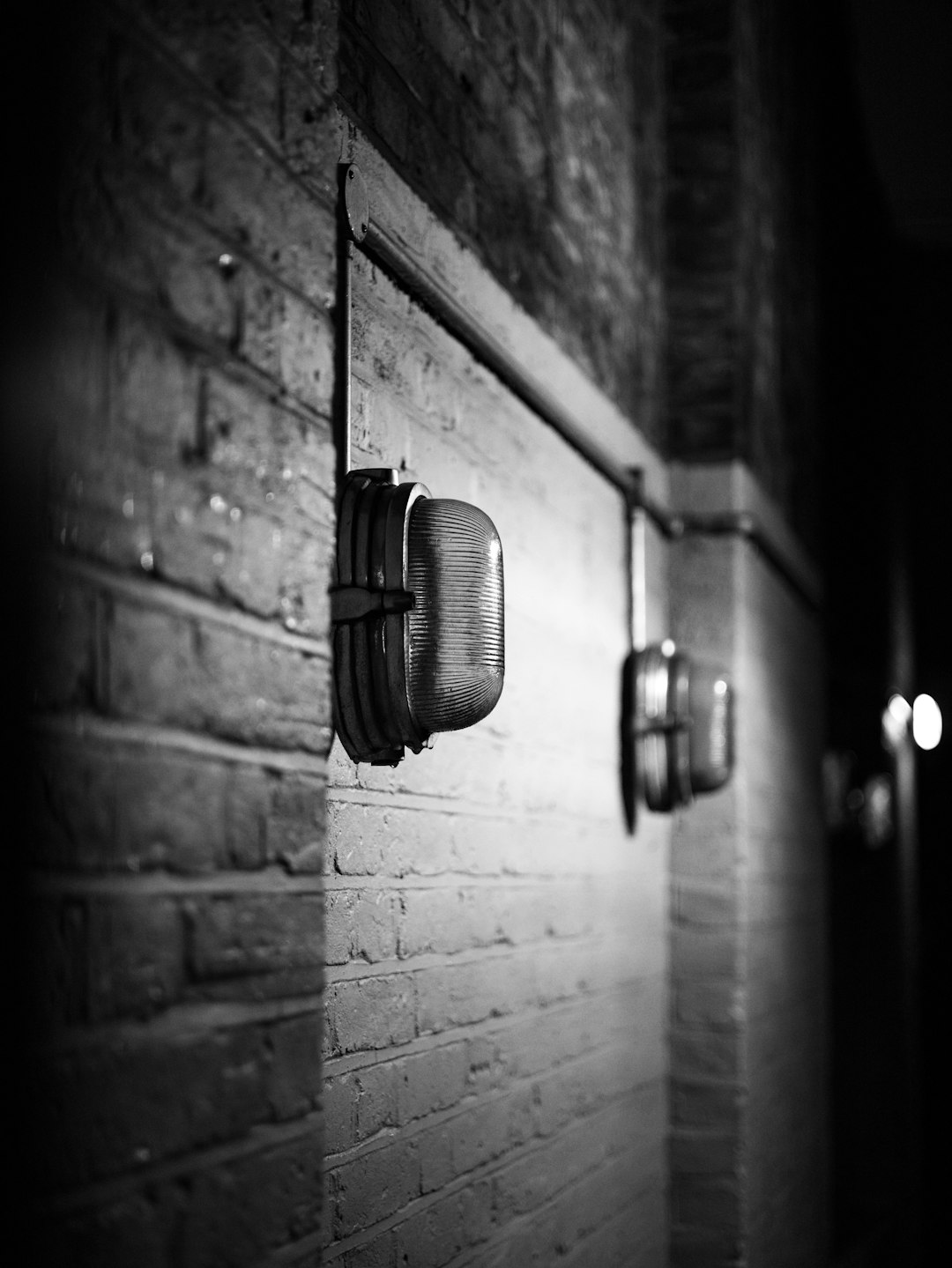 grayscale photo of wall mounted lamp