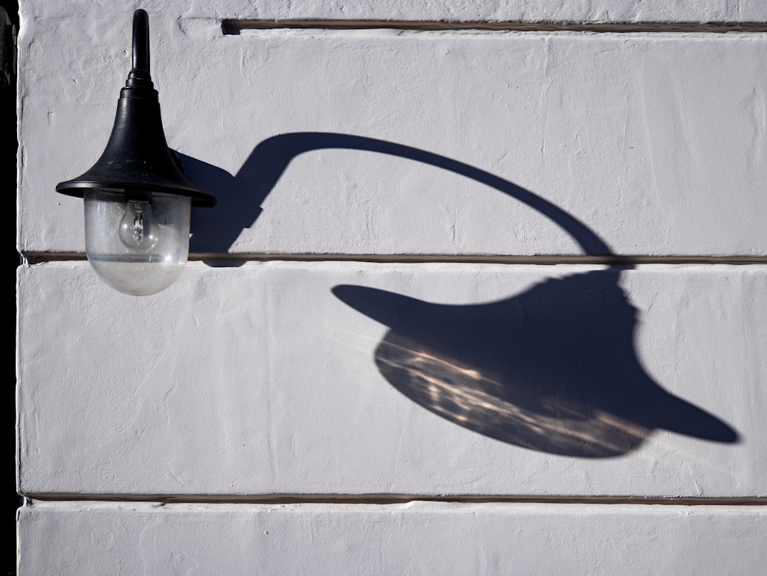 black metal lamp post on white concrete wall