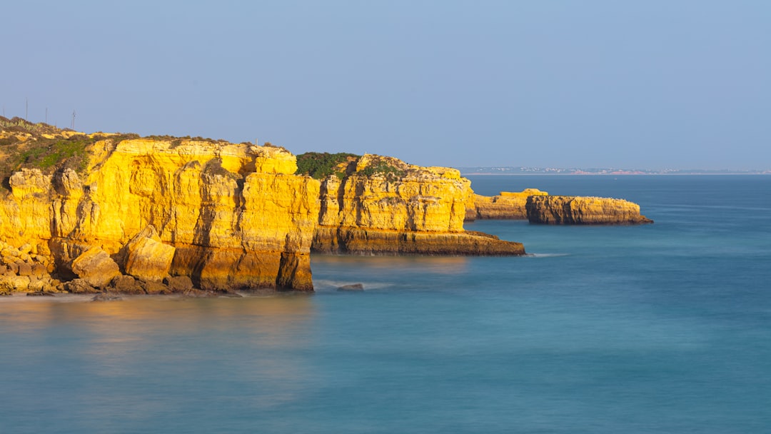 brown and green rock formation on sea under blue sky during daytime