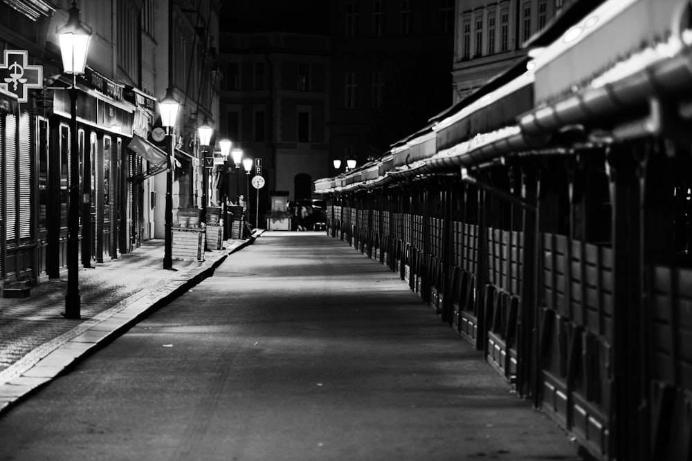 grayscale photo of street with cars parked on side